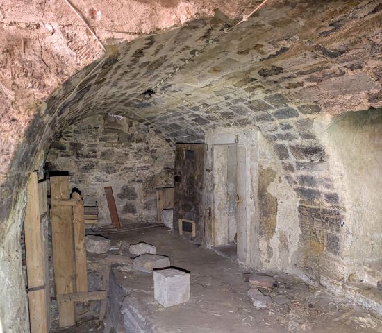 Überwölbter Kellerraum, Boden: Sand teilweise Steinplatten; Wände: unregelmäßiges Bruchsteinmauerw., gespitzte Oberfläche; Gewölbe aus sorgfältig bearbeiteten Sandsteinquadern