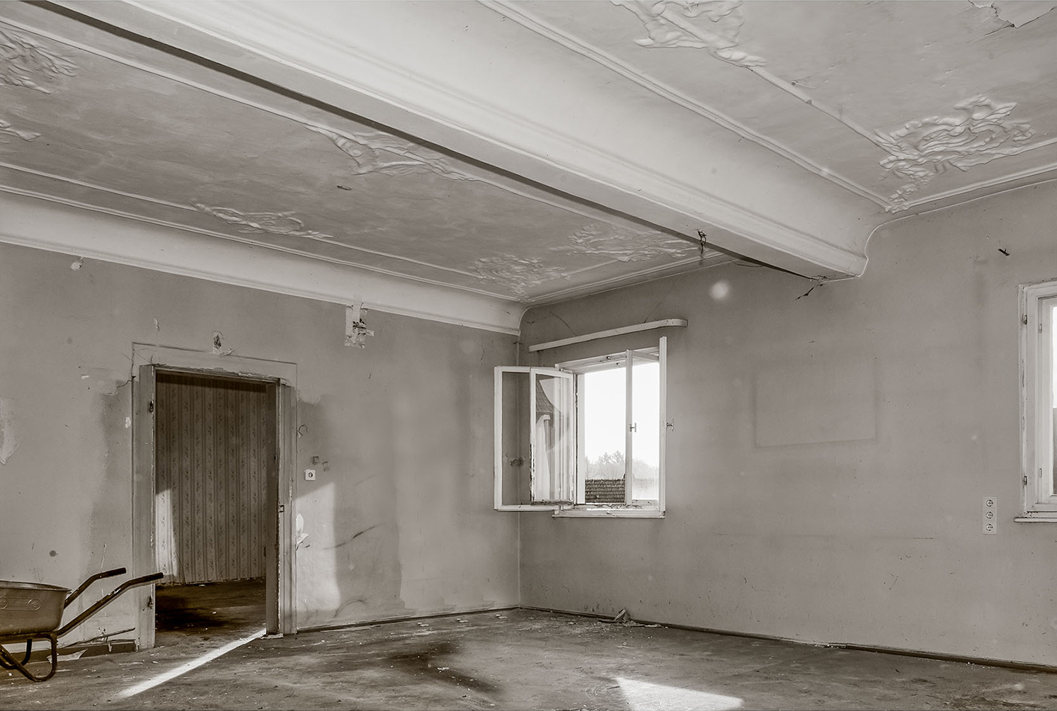 Stuckdecke mit Unterzug: beidseitig angeordnete Hohlkehlen vermitteln den fließenden Übergang zur Deckenfläche, wodurch die konstruktive Schwere optisch abgemildert wird.